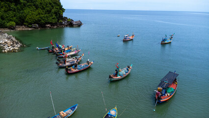 Obraz premium Aerial drone view of traditional colorful thai old wooden fishing boats on shore during low tide. Traditional Thai long-tailed fishing boats in tropical sea