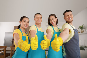 Group of young janitors showing thumbs-up in kitchen
