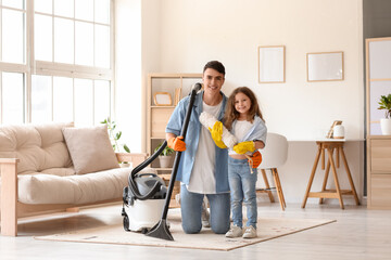 Young father and his daughter with vacuum cleaner and pp-duster at home