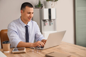 Fototapeta premium Handsome businessman working with laptop at desk in office