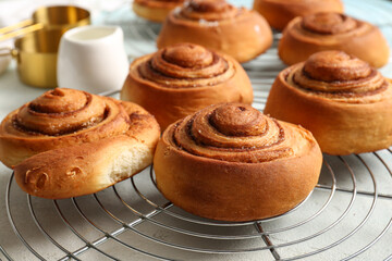 Stand with sweet cinnamon rolls on light blue background