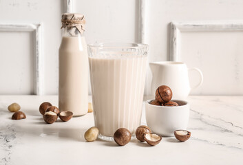Glass and bottle of fresh macadamia milk on white background