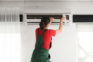 Female technician repairing air conditioner at home