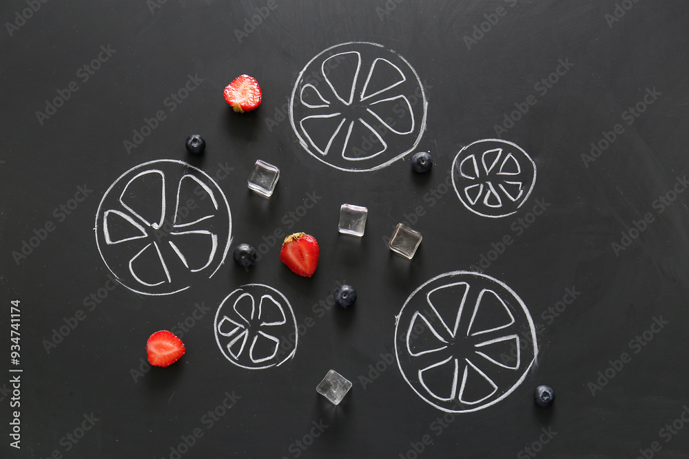 Poster Berries, ice cubes and drawn sliced citrus fruits on black background