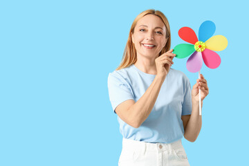 Mature woman with toy windmill on blue background