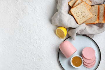 Plate with slices of tasty boiled sausage, bread and mustard sauce on grunge white background