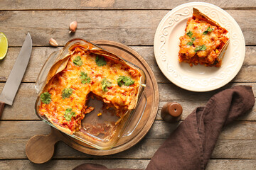 Composition with tasty enchilada and spices on wooden background