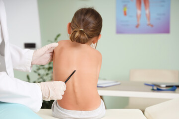 Female osteopath working with little patient on couch in clinic, back view