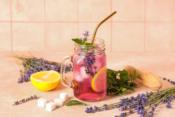 Mason jar of fresh lavender lemonade with mint and wooden juicer on beige table