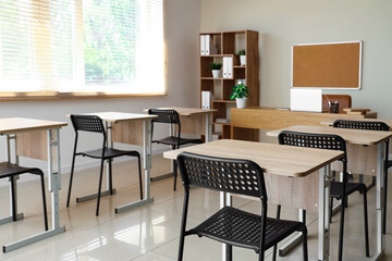 Interior of empty classroom with desks and chairs at school