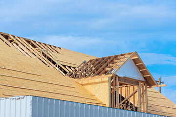 Assembling roof of new house under construction using plywood on wooden trusses