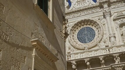 Intricate facade of a historic baroque church in lecce, puglia, italy, featuring detailed stone carvings and a large circular stained-glass window under a clear blue sky. - Powered by Adobe