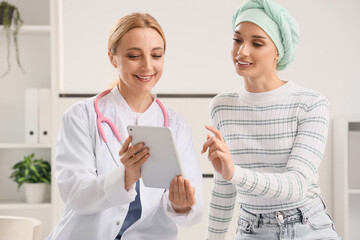 Young woman after chemotherapy with doctor using tablet computer in clinic