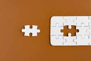 Top view of unfinished jigsaw puzzle on chocolate brown background. Business concept.