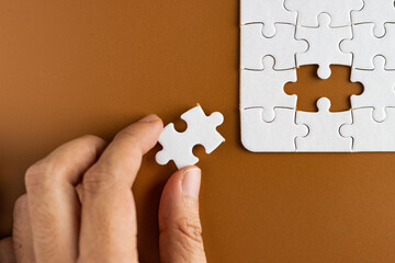 Hand holding puzzle pieces, completing jigsaw puzzle. business concept. Selective focus.