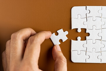 Hand holding puzzle pieces, completing jigsaw puzzle. business concept. Selective focus.