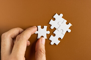 Hand holding puzzle pieces, completing jigsaw puzzle. business concept. Selective focus.
