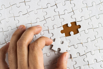 Hand holding puzzle pieces, completing jigsaw puzzle. business concept. Selective focus.