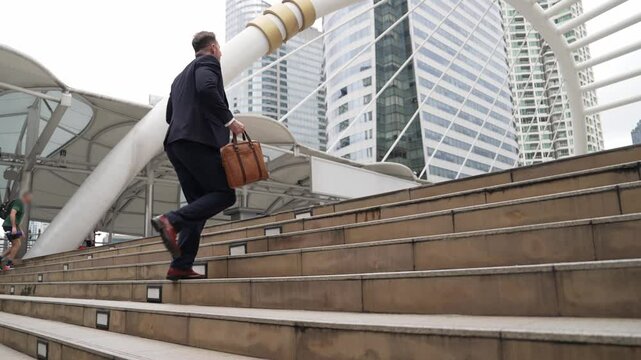 Smart caucasian businessman walking up stairs surrounded by urban view. Side view of ambitious project manager finding challenging job or investment opportunity at city with modern building. Urbane.