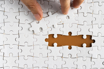 Hand holding puzzle pieces, completing jigsaw puzzle. business concept. Selective focus.