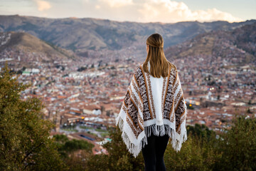 
Young woman wearing a traditional Peruvian poncho looking at the city from a well-known viewpoint...