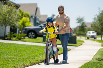 Obraz premium Happy fathers day. Father and son learning to ride a bicycle having fun together at Fathers day. Father teaching his son cycling on bike in american neighborhood. Father and son concept. Father