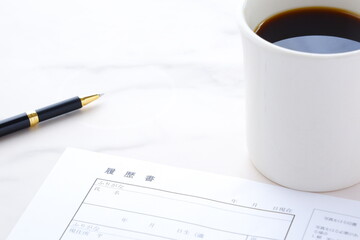 コーヒーを飲みながら、履歴書を書く
