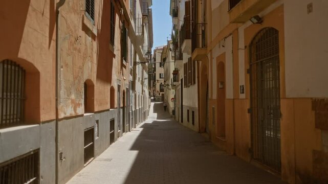 Narrow street in palma mallorca with old buildings casting shadows in a sunlit pedestrian area showcasing mediterranean architecture with a sense of rustic charm and urban tranquility
