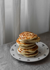 A stack of pancakes on a plate on the table - a delicious breakfast, dessert, snack