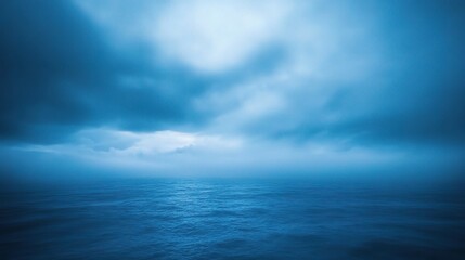 Obraz premium Deep Blue Enigma: An ethereal expanse of the sea stretches out under a brooding sky, the swirling clouds casting a mysterious blue hue over the water. 