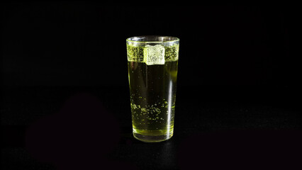 Lemonade with Rising Bubbles and Ice Cubes in Glass on a Black Background