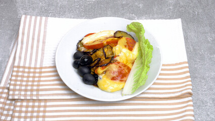 Fried Tomatoes and Eggplants with Olives and Herbs on a Plate
