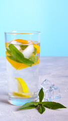 A glass of cold water with ice, lemon, and mint on a white table