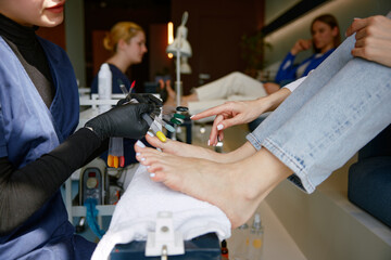 View from above on client choosing color for nail during pedicure