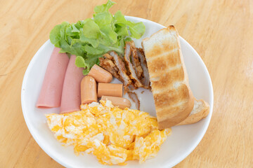 A delicious breakfast plate featuring scrambled eggs, sliced meat, lettuce, and toasted bread, perfect for a hearty morning meal.