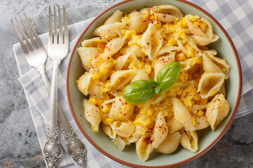 Creamy corn pasta features a silky sauce made from corn as well as pops of juicy kernels for texture closeup in the bowl on the table. Horizontal top view from above