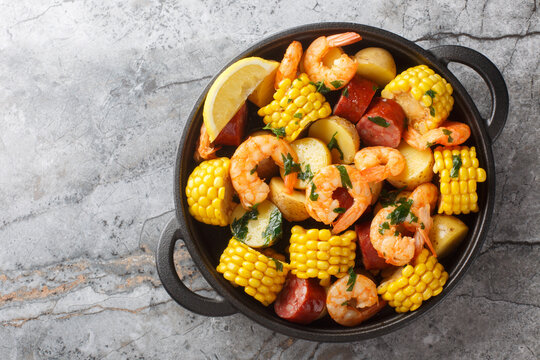 Homemade Cajun Seafood Boil with shrimp, corn, baby potatoes, sausage and lemons closeup on the table. Horizontal top view from above