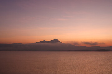 Photographs of intricate mountain ranges at sunset The golden rays of the sun shone on the surface of the water.  The shadow of the mountain reflected on the surface of the water. Gives a feeling of r