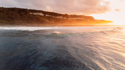 Bali coastline, ocean on low tide and waves with sunrise. Panoramic drone view