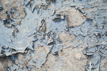 a concrete wall with old cracked flaking paint. Weathered rough painted surface with patterns of cracks and peeling.