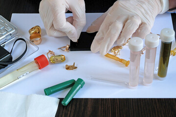 A pawn shop employee tests old gold jewelry using reagents and a touchstone, Buying old gold