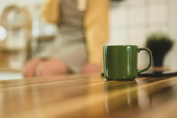 A green coffee cup on wooden countertop in kitchen