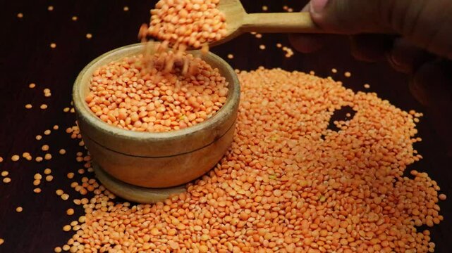 Taking red lentils by spoon from a bowl. Macro. legumes drops.  Vegetarian Healthy Food.