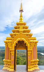 The golden yellow temple gate arch of Wat Phra That Doi Phra Chan is carved with delicate patterns typical of Lanna art. The door opened to reveal the beautiful scenery behind. Consists of mountains a