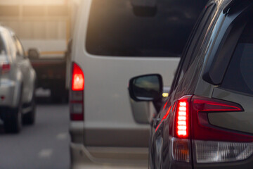 Rear side of car on the aspahlt road. Transtport of car turn on brake light in the business time environment of moring time. Traffic congestion and queues of cars.