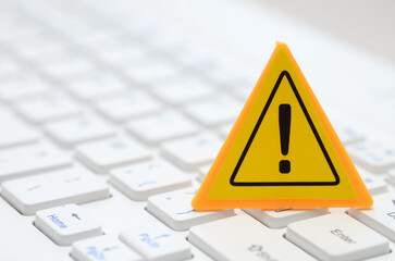 The image of a yellow warning sign on a computer keyboard serves as a visual cue, alerting users to potential cybersecurity threats