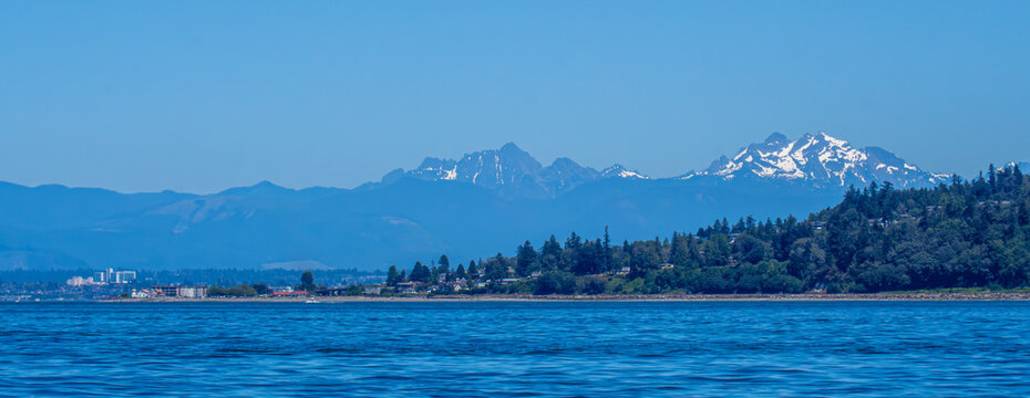 Hat Island in front of the summer Cascade Mountain range near Everett, Washington as seen from the waters of Puget Sound.