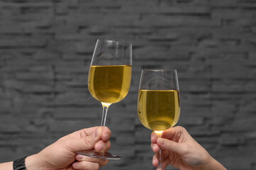 Toast wznoszony białym winem na tle szarej ściany z cegły  © Paweł Kacperek