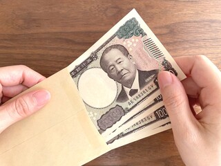 茶封筒に入ったお金を持つ女性の手元