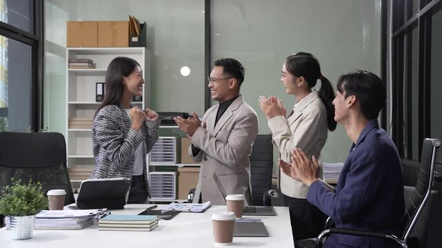 In an office, an Asian team meets at a desk, analyzing financial data on a monitor. They discuss business finance, operational guidelines, and strategies for success, data-driven decision-making.